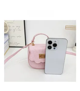 Mini sac à main rose effet crocodile présenté à côté d'un téléphone pour comparer la taille