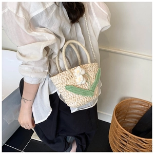 Detail of hand-woven straw bag with crochet flowers and pearl chain for summer vacation