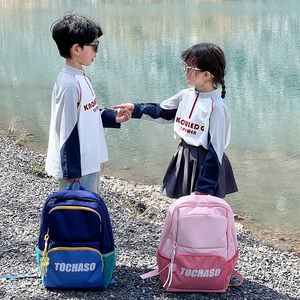 Kids large contrast color school backpacks in blue and pink with cute charms by lake
