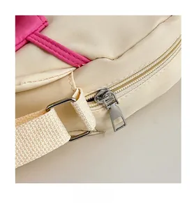 Gros plan sur la fermeture éclair fluide et le liseré rose du sac en nylon blanc cassé