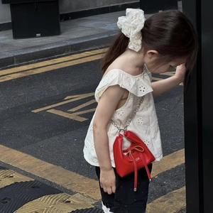 Detail of red leather crossbody bag with bow drawstring and silver chain strap