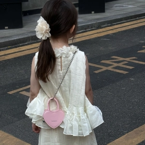 Détail du mini sac à bandoulière rose en forme de cœur avec chaîne argentée en ville