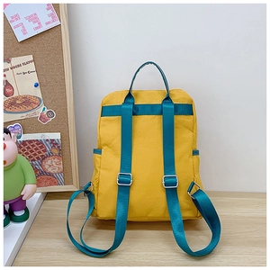 Detail of bright yellow kids backpack featuring contrasting blue straps and metal buckles