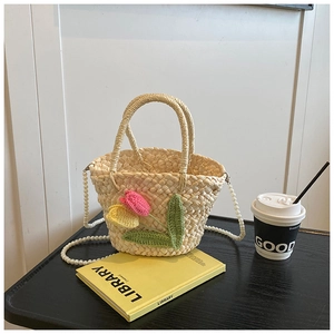 Detail of straw woven handbag with crochet tulips and elegant faux pearl shoulder strap