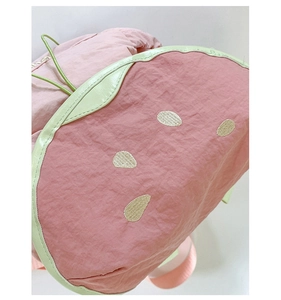 Close-up of pink watermelon backpack with seed embroidery and light green piping detail