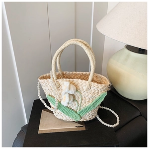 Detailed shot of handmade straw bag featuring crochet floral accents and pearl chain strap