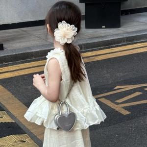 Vue de dos d'un enfant portant un mini sac cœur argenté et une pince à cheveux fleur blanche