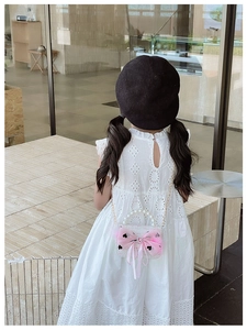 Detail of girls white lace hollow dress with a pink pearl bow handbag in close-up shot