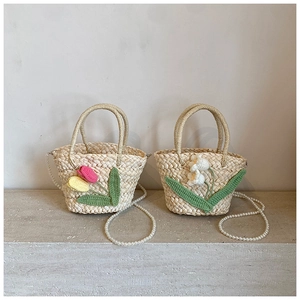 Detail of handmade straw mini bags featuring crochet flowers and pearl bead straps