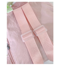 Close-up of pink nylon backpack featuring light green handle and transparent strap buckles