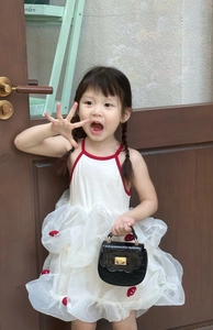 Détail des appliqués fraises rouges sur la robe en tulle blanc avec mini sac noir