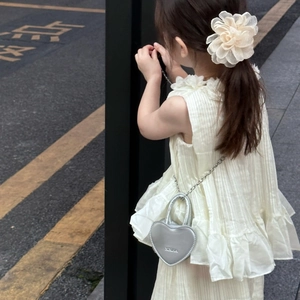 Mini sac bandoulière argenté en forme de cœur avec chaîne sur une robe blanche