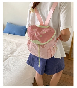 Rear view of a watermelon themed pink nylon backpack with green trim and seed embroidery