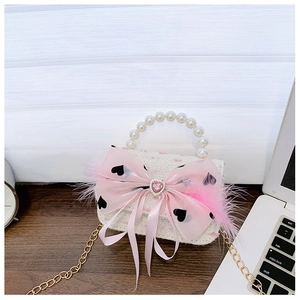 Detail of pink tweed girl's bag with pearl handle, satin bow, and feather accents