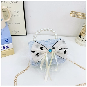 Detail of blue tweed girl bag with pearl handle, heart bow, and feather accents