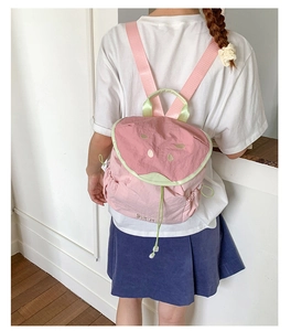 Detail shot of a pink watermelon-shaped kids backpack with green trim and golden seed embroidery