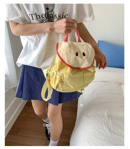 Detail of creative yellow apple-shaped backpack with embroidery and drawstring closure
