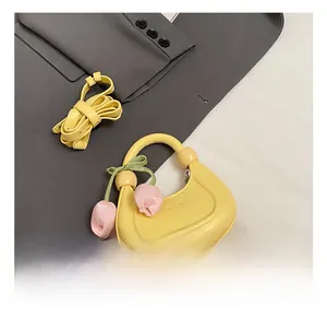 Detail view of yellow crescent handbag with tulip charm and adjustable shoulder strap