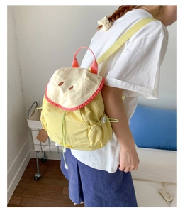 Detail of cute yellow apple-themed backpack showing the side drawstring and Apple embroidery