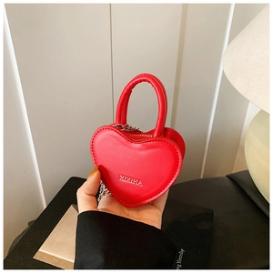 Détail du mini sac rouge en forme de cœur avec chaîne argentée et poignée supérieure