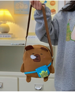 Détail du sac bandoulière Capybara avec pendentif tortue verte et poche avant bleue