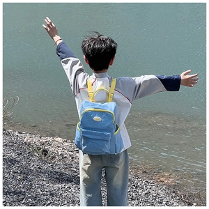 Blue and yellow kid backpack shown in an outdoor scenic setting for travel and hiking