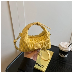 Detail der gelben Mini-Handtasche mit Metalllogo und Matelassé-Faltenstruktur