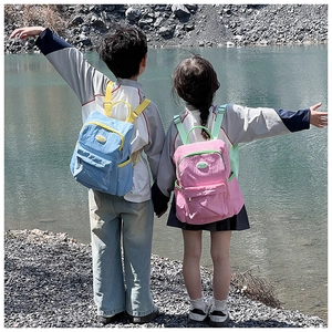 Outdoor shot of water-resistant nylon kids backpacks in bright blue and pink colors