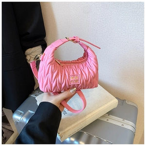 Detail der rosa gefalteten Mädchenhandtasche mit Goldlogo und Schultergurt