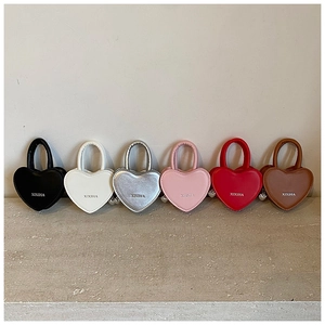 Détail de mini sacs en bandoulière en forme de cœur en diverses couleurs avec breloques