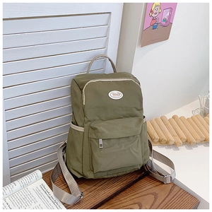 Detail view of olive green kids backpack featuring a front pocket and circular logo patch