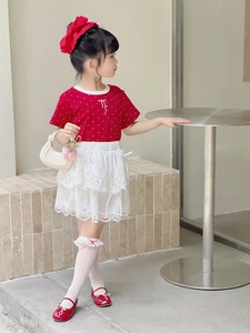 Close-up of red polka dot t-shirt with white lace skirt and sweet bow hair accessory