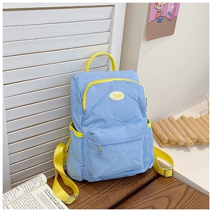 Close-up of light blue kids backpack with yellow contrast straps and side pockets on desk
