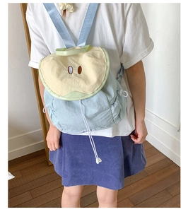 Detail view of the apple-shaped backpack with beige flap and blue drawstring closure