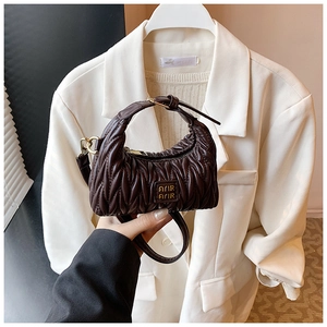 Makroaufnahme der gesteppten Schokotasche mit Goldlogo und eleganten Falten-Details