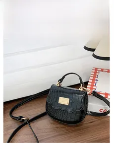 Détail du mini sac à main noir effet crocodile avec plaque dorée et poignée élégante