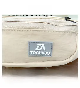 Dettaglio della toppa in gomma beige TOCHASO e della cerniera sulla borsa a tracolla bimbo