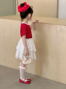 Detail of a minimalist cream-colored crescent handbag paired with a red polka dot girls' outfit