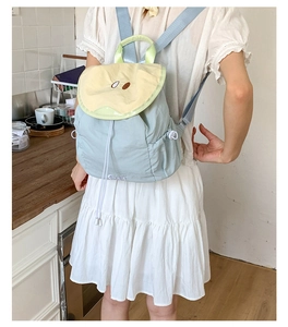 Detail view of stylish light blue and yellow contrast backpack worn by model in home setting
