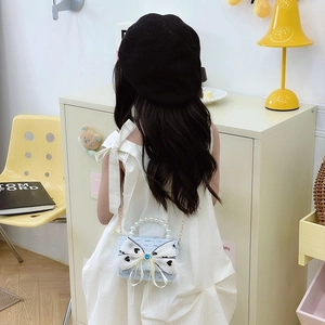 Light blue tweed girls shoulder bag with pearl handle and bow in an elegant room