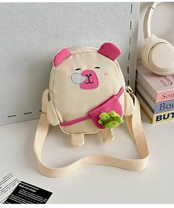 Détail du sac ours crème avec broderie rose et une breloque en peluche de grenouille verte