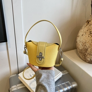 Detail der leuchtend gelben Mini-Eimertasche mit Webstruktur und silbernem Drehverschluss