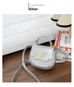 Détail du mini sac argenté avec motif crocodile, rabat festonné et finitions dorées