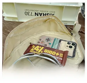 Dettaglio del marsupio in nylon beige che mostra la capacità interna e le tasche