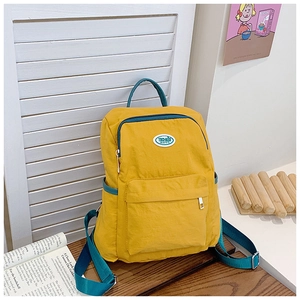 Close-up of yellow and blue kids backpack with round brand logo on wooden table