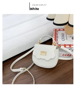 Détail du sac selle blanc à motif crocodile avec bord ondulé et plaque en métal doré