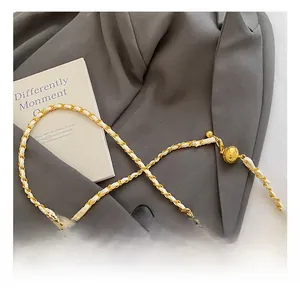 Close-up of golden metal chain strap with woven leather and adjustable ball buckle