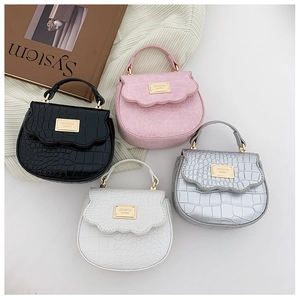 Gros plan sur la texture crocodile et le rabat ondulé des mini sacs à main pour filles