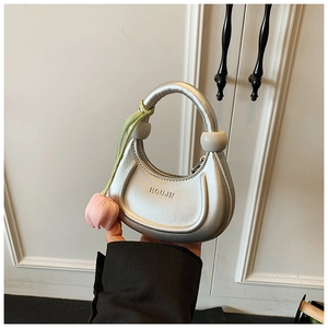 Close-up of a silver crescent handbag for kids with a pink tulip charm accessory