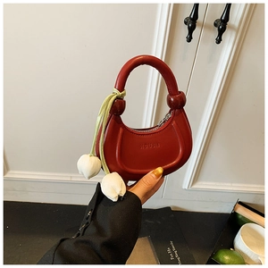 Detail of red crescent mini handbag for kids featuring a white tulip charm and ribbon